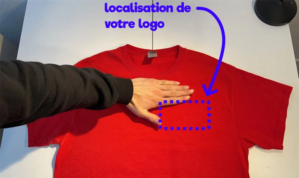 Main posée sur un t-shirt rouge pour repérer l'emplacement du logo, encadré en pointillés bleus