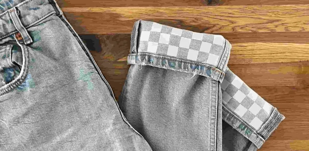 Ourlets de jean gris retroussés, décorés d'un motif damier en flex gris et blanc