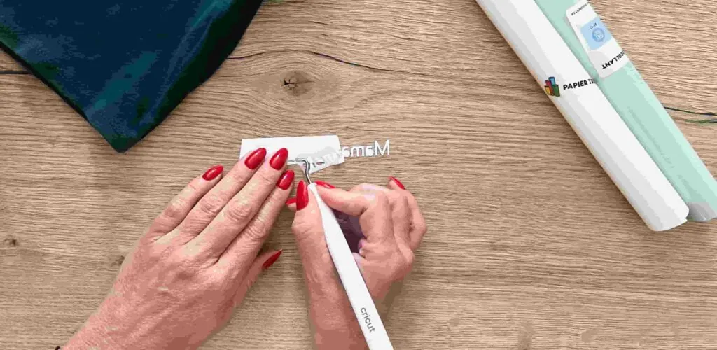 Échenillage au crochet Cricut d'un texte en flex blanc découpé en miroir, rouleaux de flex Papier Transfert à côté