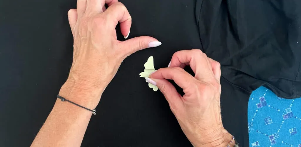 Positionnement d'un oiseau découpé dans du flex jaune pâle sur un t-shirt noir avant pressage