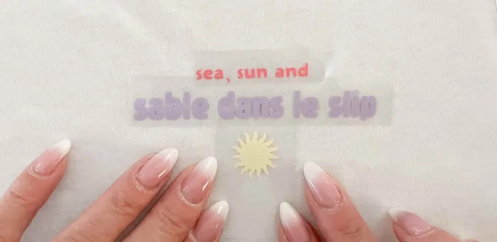 Application du flex « sea, sun and sable dans le slip » rose et lilas avec soleil jaune sur un t-shirt blanc