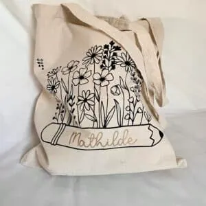 Tote bag écru floqué d'un bouquet de fleurs noir sur un crayon au prénom « Mathilde »