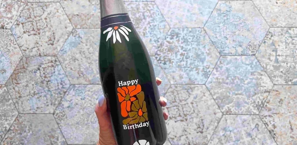 Bouteille noire personnalisée « Happy Birthday » avec fleurs en vinyle adhésif blanc, orange et kaki