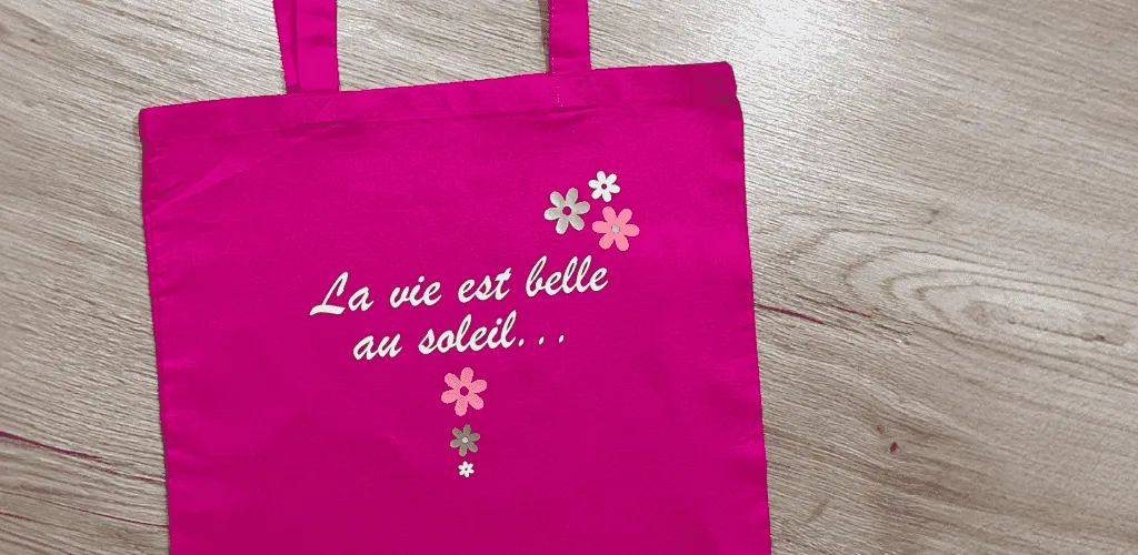 Tote bag fuchsia floqué « La vie est belle au soleil… » en flex blanc avec petites fleurs
